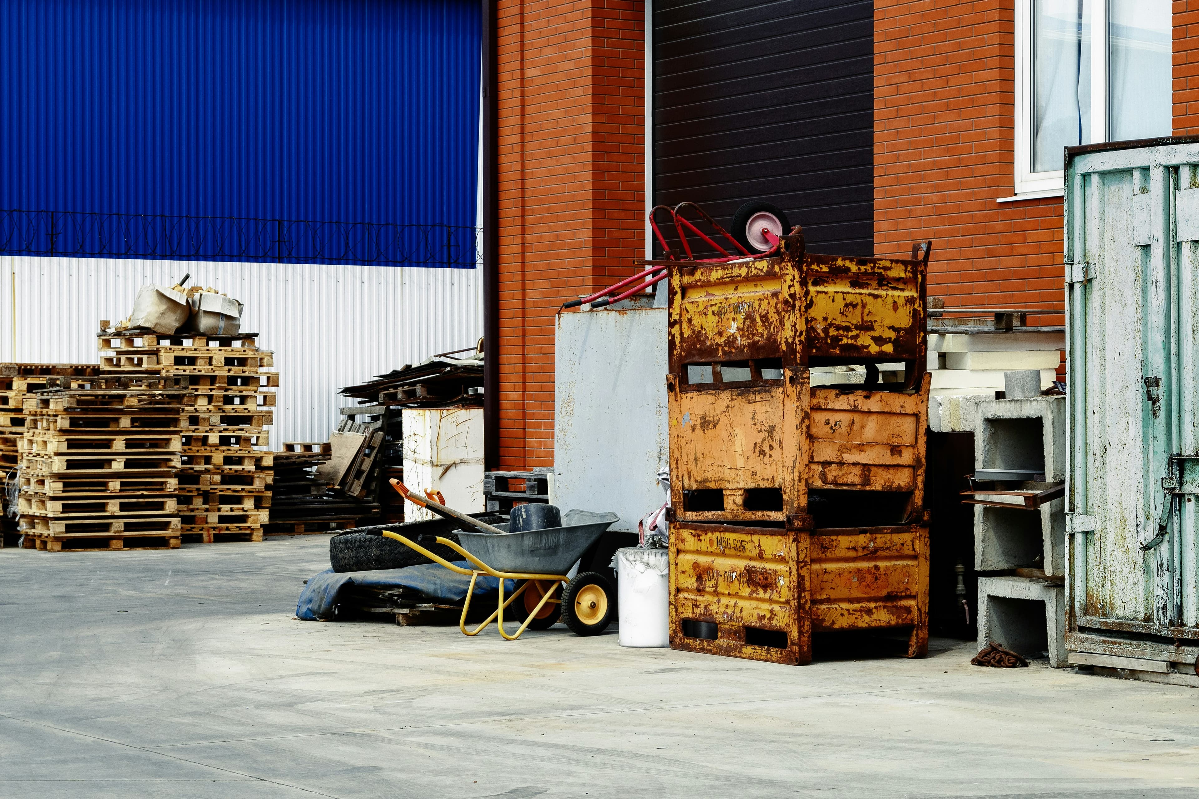 Warehouse yard with stacked pallets and metal containers awaiting clearance